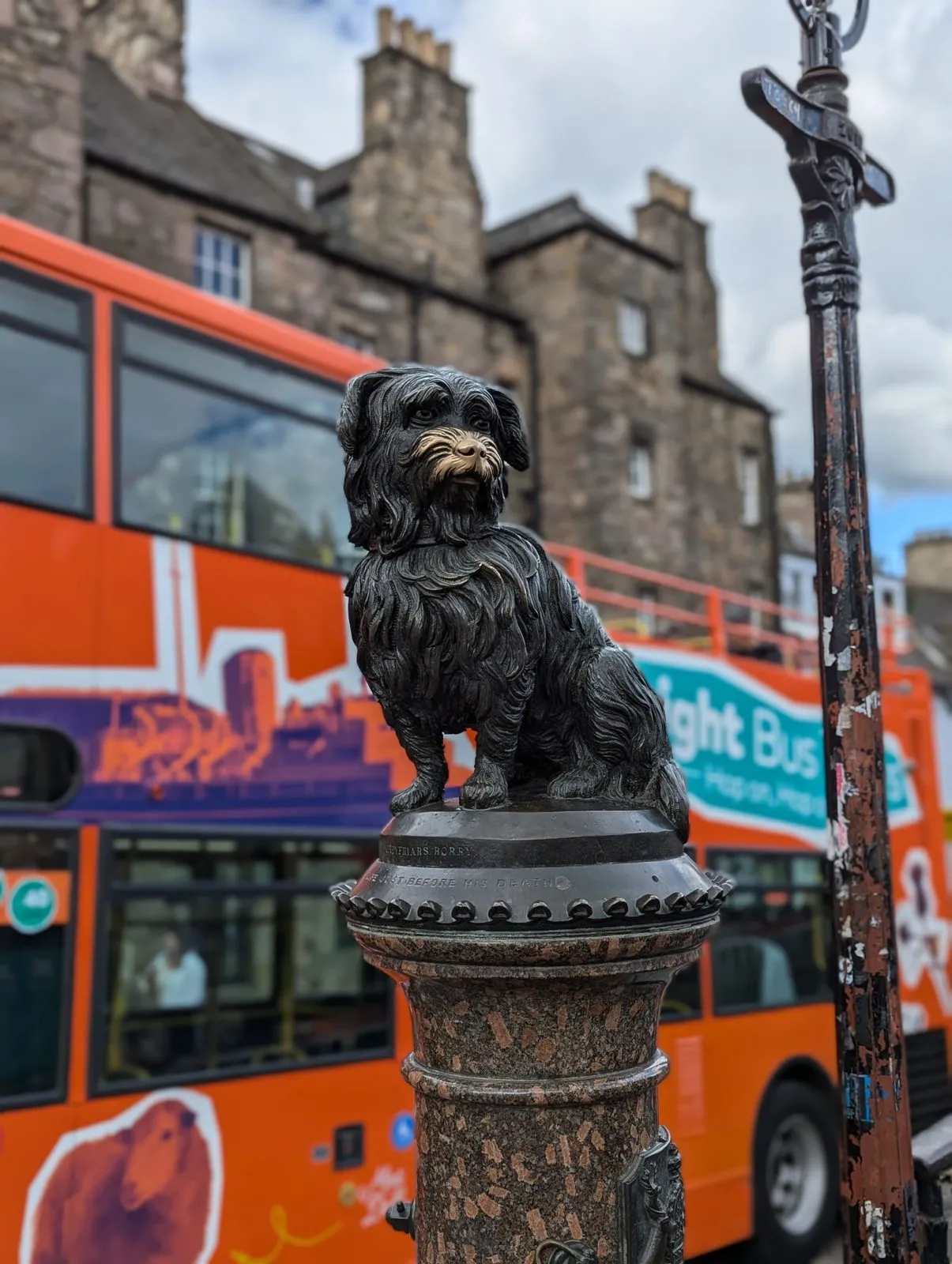 Een hop-on hop-off bus rijdt langs het standbeeld van Greyfriars Bobby