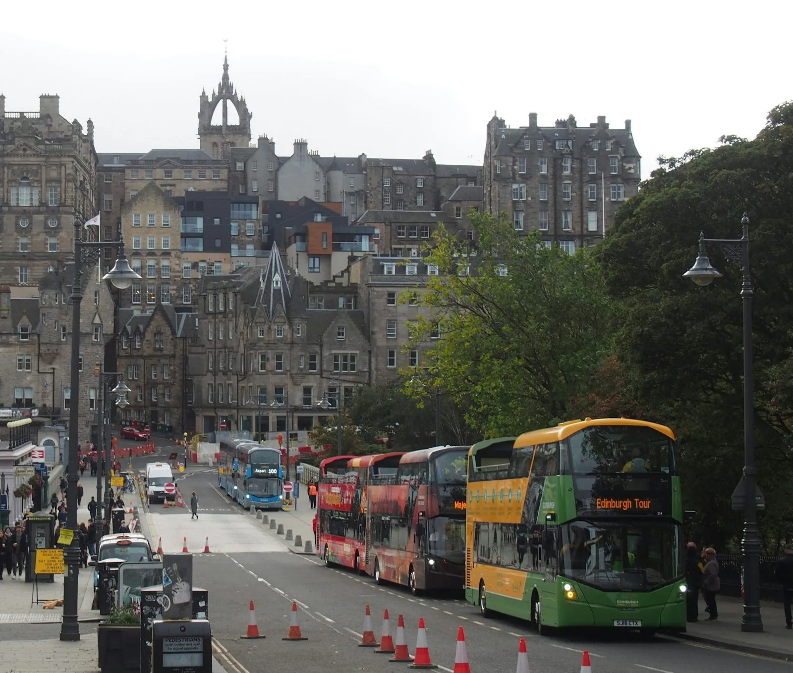 Hop-on hop-off bussen met een open bovendek in de rij op Waverley Bridge, met de Old Town erachter